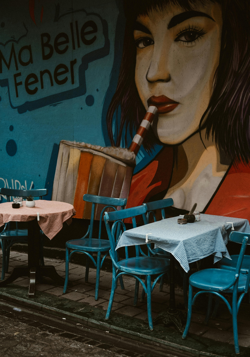 empty table and chairs front of wall painting