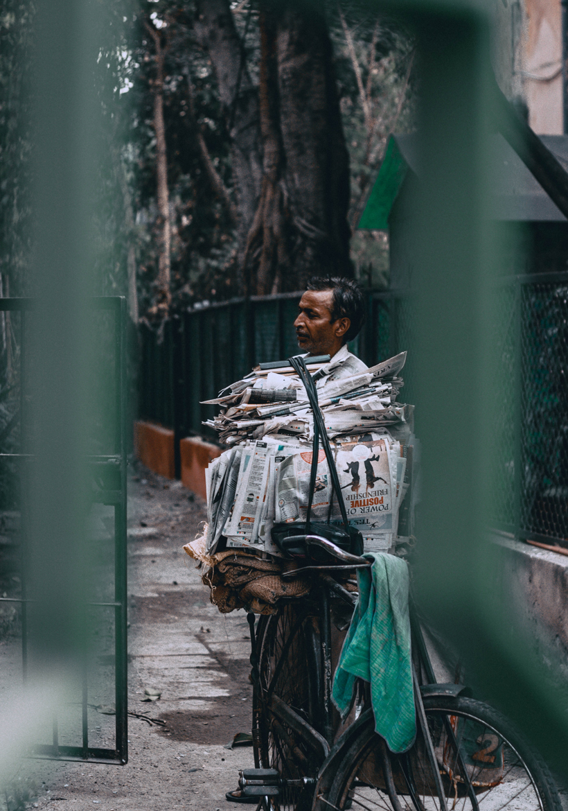 man standing with his bicycle with bundle of newspapers